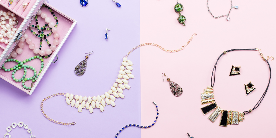 Different types of jewelry laid on a purple and pink surface